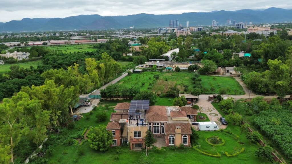 Aerial view of Ali Farms in H-9, Islamabad, with the 30 kW solar installation and the Margalla Hills behind